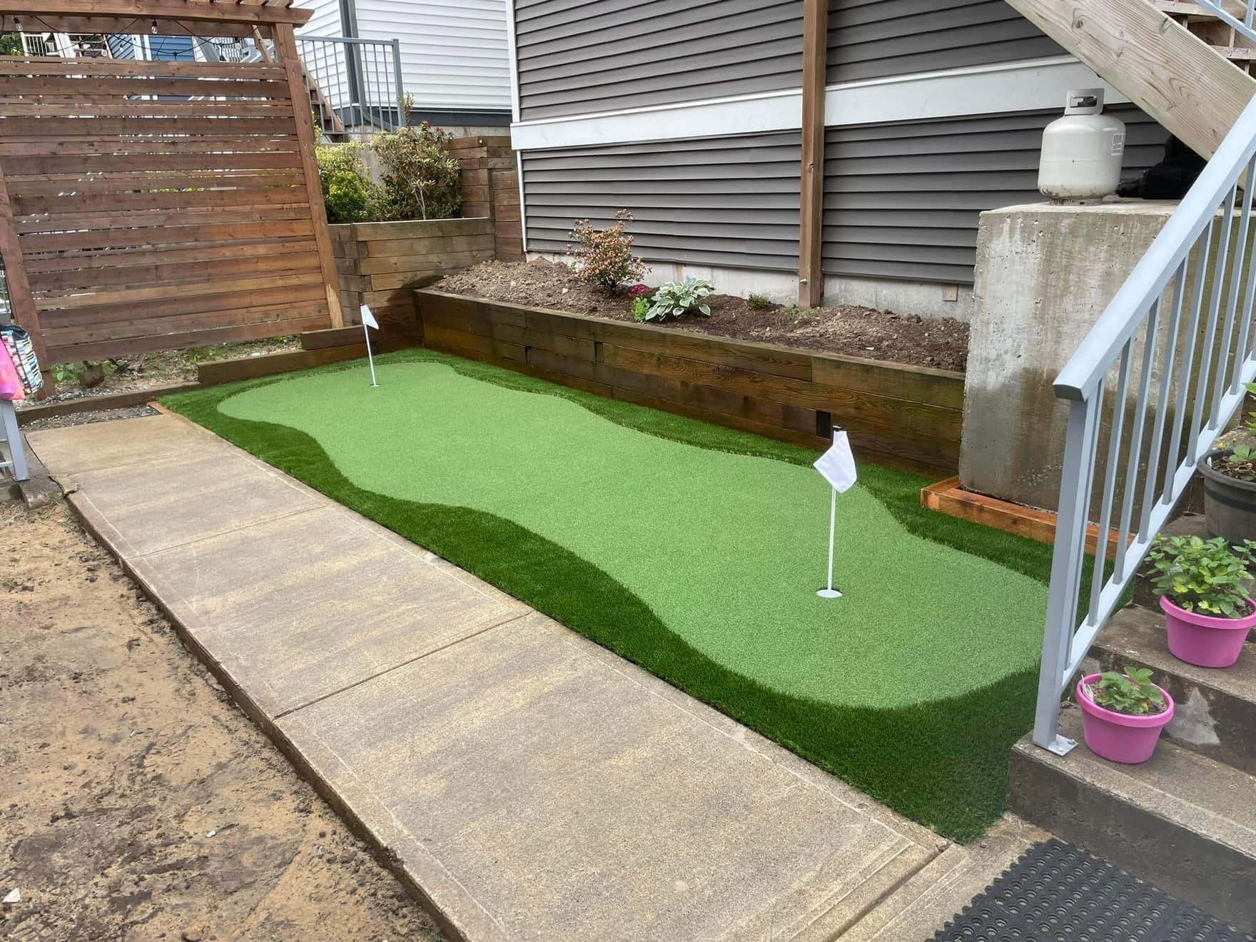 a narrow backyard fitted with a putting green featuring two holes